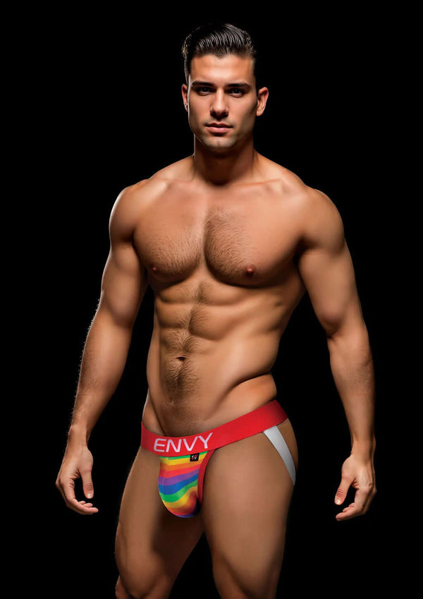 Man wearing Envy Rainbow Pride Jock Strap with red waistband and vibrant rainbow pouch, showcasing bold and breathable design.