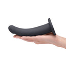 B-vibe Essentials 7 Inch Smooth Silicone Dildo Black held in hand, showcasing its sleek design and soft silicone material.