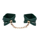 Sex & Mischief Indica Cutout Cuffs made of emerald green faux leather with gold hardware and chain.
