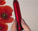 Poppy Red Rechargeable Bullet Vibrator held in hand with red poppy flowers in the background.