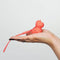 Hand holding Unihorn Mini Peachy Pony vibrator, pocket-sized and orange, showcasing its cute design and compact size.