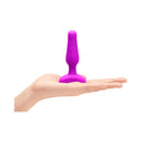 b-Vibe Novice Remote-Controlled Vibrating Anal Plug Fuchsia in a hand for scale, showcasing its compact design.