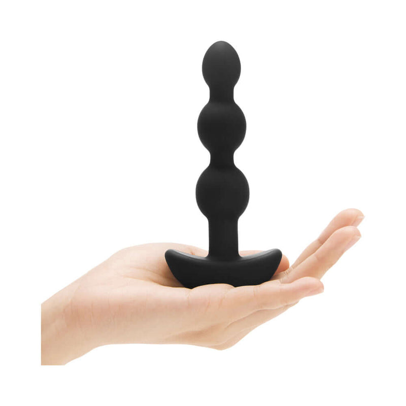 b-Vibe Triplet Remote Controlled Anal Beads Plug Black held in hand showcasing its flexible design and tapered shape.