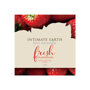 Intimate Earth Fresh Strawberry Flavored Lubricant 3ml in a foil packet with fresh strawberries background.