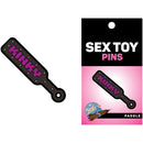 Wood Rocket Kinky Paddle Enamel Lapel Pin Black and Gold on packaging, playful design featuring 'Kinky' in pink letters.