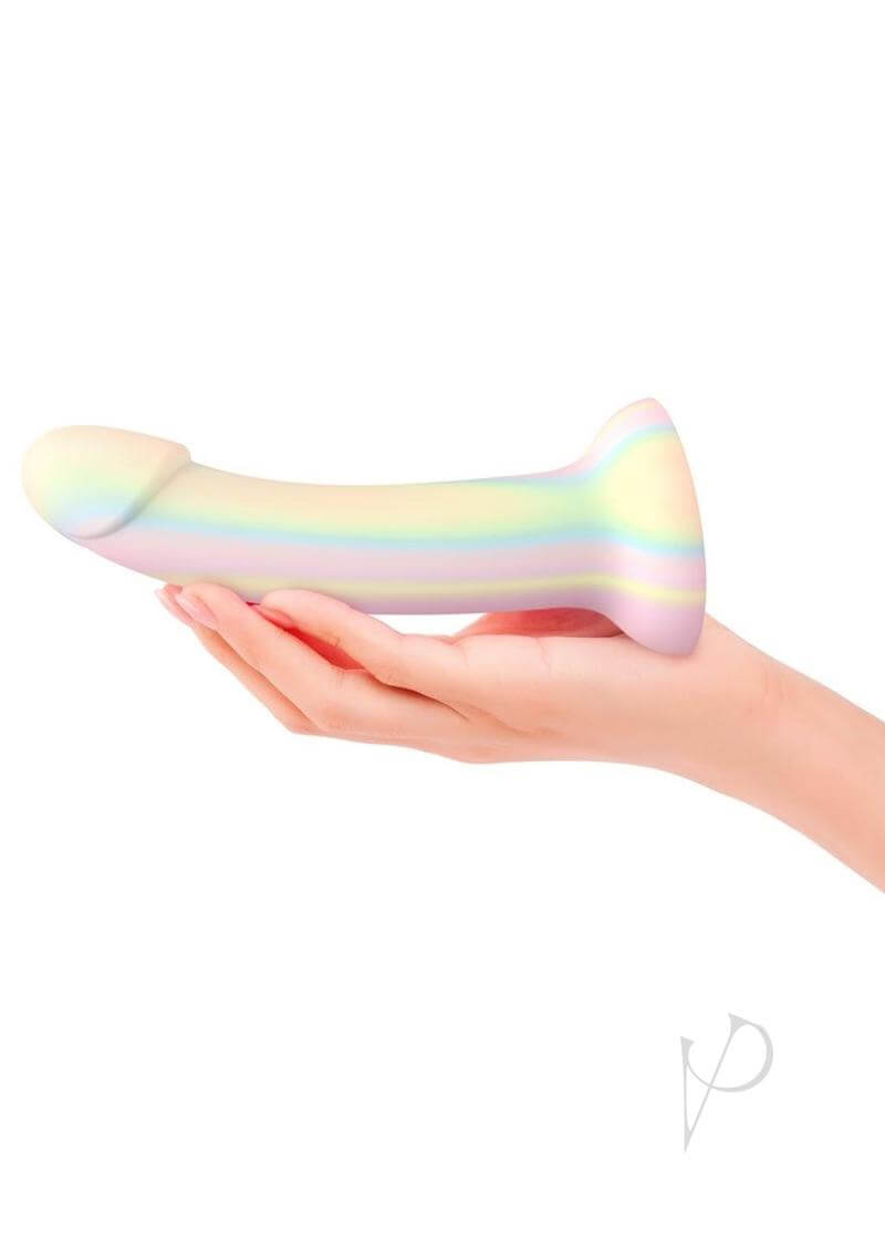Dildolls Fantasia Silicone Dildo Glow In The Dark held in hand, showcasing its pastel rainbow design.
