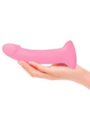 Dildolls Glitzy Silicone Dildo Pink held in hand, showcasing its smooth, vibrant pink design and soft silicone texture.
