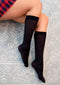 Leg Avenue Nylon Knee Hi in black, styled with a plaid skirt, showcasing elegance and comfort.