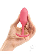 B-Vibe Snug Plug 2 Silicone Weighted Anal Plug Coral held in hand, showcasing its ergonomic design in vibrant coral.
