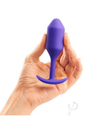 B-Vibe Snug Plug 2 Silicone Weighted Anal Plug Purple held in hand, showcasing its design and texture.