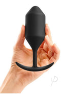 B-Vibe Snug Plug 4 Silicone Weighted Anal Plug Black held in hand, showcasing its sleek design and comfort.