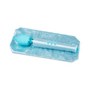 Le Wand All That Glimmers Petite Massager Set Light Blue on a blue glittery surface, showcasing its luxurious design.