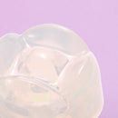 Close-up of Iroha Petit Lily Disposable Clitoral Massager Clear with soft, jelly-like texture against a purple background.