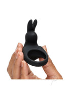 Happy Rabbit rechargeable cock ring in black with bunny ears, held in a hand, showcasing its flexibility and design.