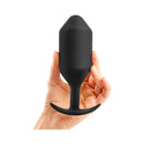 b-Vibe Snug Plug 7 Weighted Silicone Anal Plug Black held in a hand, showcasing its seamless design.