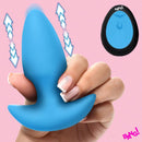 Close-up of the Bang Thrusting & Vibrating Silicone Butt Plug Blue held in a hand, showcasing its smooth design and wireless remote.