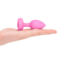 b-Vibe Vibrating Heart Anal Plug Small Medium Pink held in a hand, showcasing its stylish design and size.