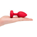 b-Vibe Vibrating Heart Anal Plug Medium Large Red in hand showcasing its smooth design and stylish heart base.