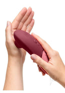 Womanizer Next Sensual Collection Air Clitoral Stimulator Red held in hands demonstrating its elegant design and features.