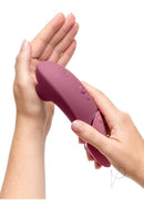 Womanizer Next Sensual Collection Air Clitoral Stimulator Pink in hands showcasing its ergonomic design.
