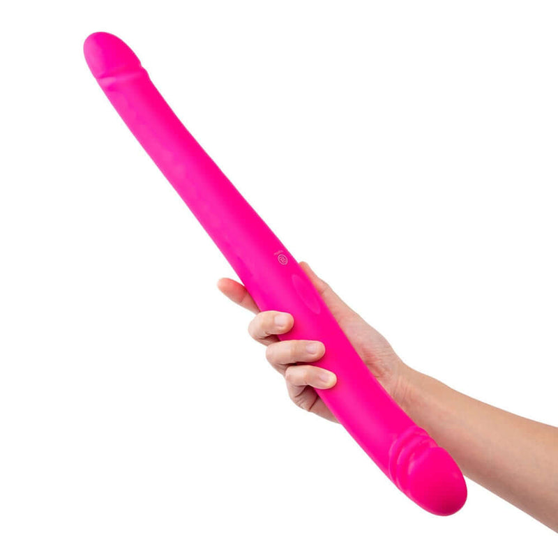 Together Duo Pink Vibrating Dildo held in a hand, showcasing its sleek design and vibrant color.