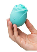 Romp Rose Glow-In-The-Dark Air Clitoral Stimulator Blue held in a hand, showcasing its unique rose design.