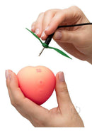 Romp Pink Peach Rechargeable Silicone Vibrator being connected for charging with hands holding the device.
