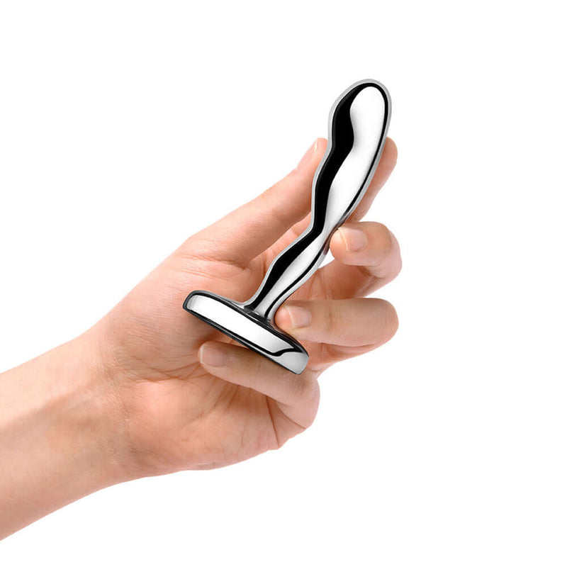 A hand holding the b-Vibe Stainless Steel Prostate Plug, a premium anal toy designed for P-spot stimulation.