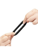 B-Vibe Flex Ring Tread Silicone Cock Ring Black being stretched between two hands.