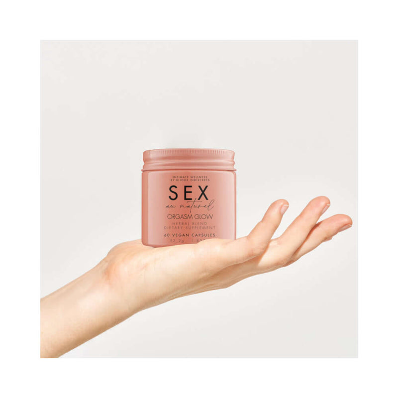Bijoux Indiscrets Sex au Naturel Orgasm Glow Supplement 60 Pc displayed in a hand, highlighting its design and packaging.