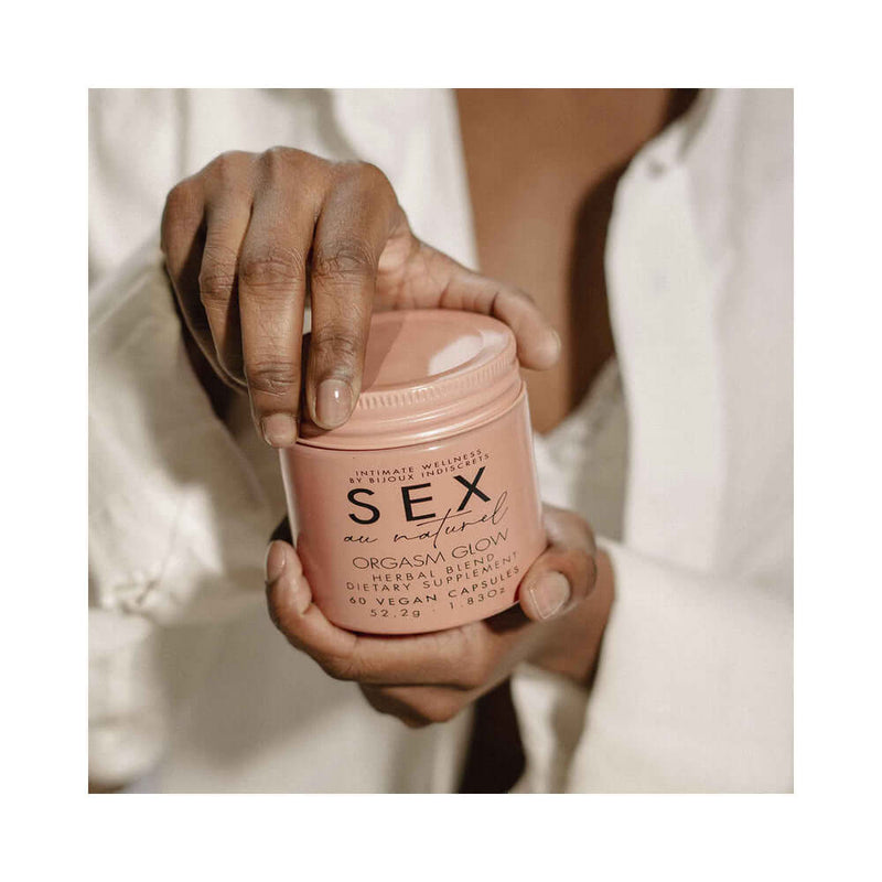 Bijoux Indiscrets Sex au Naturel Orgasm Glow Supplement 60 Pc in a hand, showcasing the product packaging beautifully.