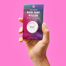 Bijoux Indiscrets Clitherapy Bad Day Killer Clitoral Balm packaging held by a hand on pink background.