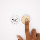 Bijoux Indiscrets Clitherapy Bad Day Killer Clitoral Balm in a jar with a finger dipping into it.