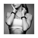 Bijoux Indiscrets Maze Thin Handcuffs Black worn as bracelets with a chain connection, showcasing elegant restraint.