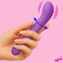 Hand holding Bang G-Spot Flexible Rechargeable Silicone Vibrator Purple against a pink background.