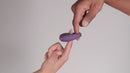 Je Joue Mio Rechargeable Vibrating Silicone Cock Ring Black held between fingers to demonstrate its design and usage.