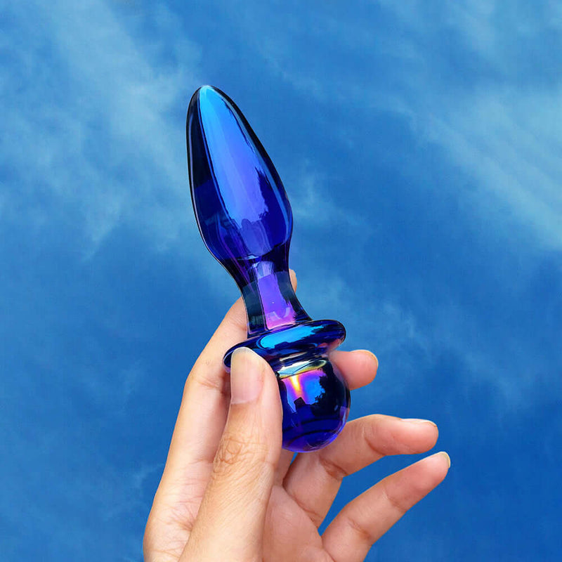 Biird Anii Glass Anal Plug Blue held in hand against a blue sky background, showcasing its elegant design.