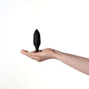 Je Joue Onyx Vibrating Butt Plug Black held in a hand against a white background.