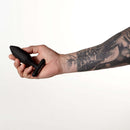Hand holding the Je Joue Onyx Vibrating Butt Plug Black against a plain background.