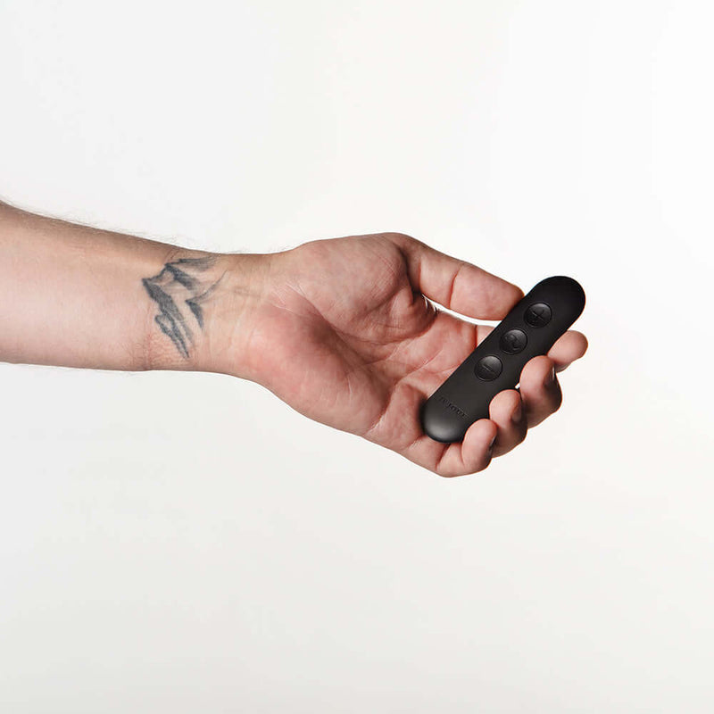 Person holding the Je Joue Onyx Vibrating Butt Plug Black remote control in a hand.