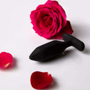 Je Joue Onyx Vibrating Butt Plug Black surrounded by rose petals for sensual pleasure.