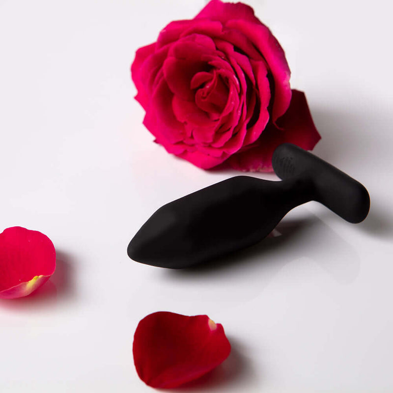 Je Joue Onyx Vibrating Butt Plug Black surrounded by rose petals for sensual pleasure.