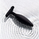 Je Joue Egon Vibrating Butt Plug Black resting on rippling water surface.
