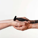 Je Joue Egon Vibrating Butt Plug Black being held by two hands, showcasing its sleek design and form.