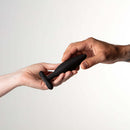 Two hands exchanging the Je Joue Egon Vibrating Butt Plug Black, a luxurious sensual toy for enhanced pleasure.
