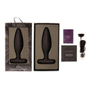 Je Joue Egon Vibrating Butt Plug Black in packaging with accessories displayed on a white background.