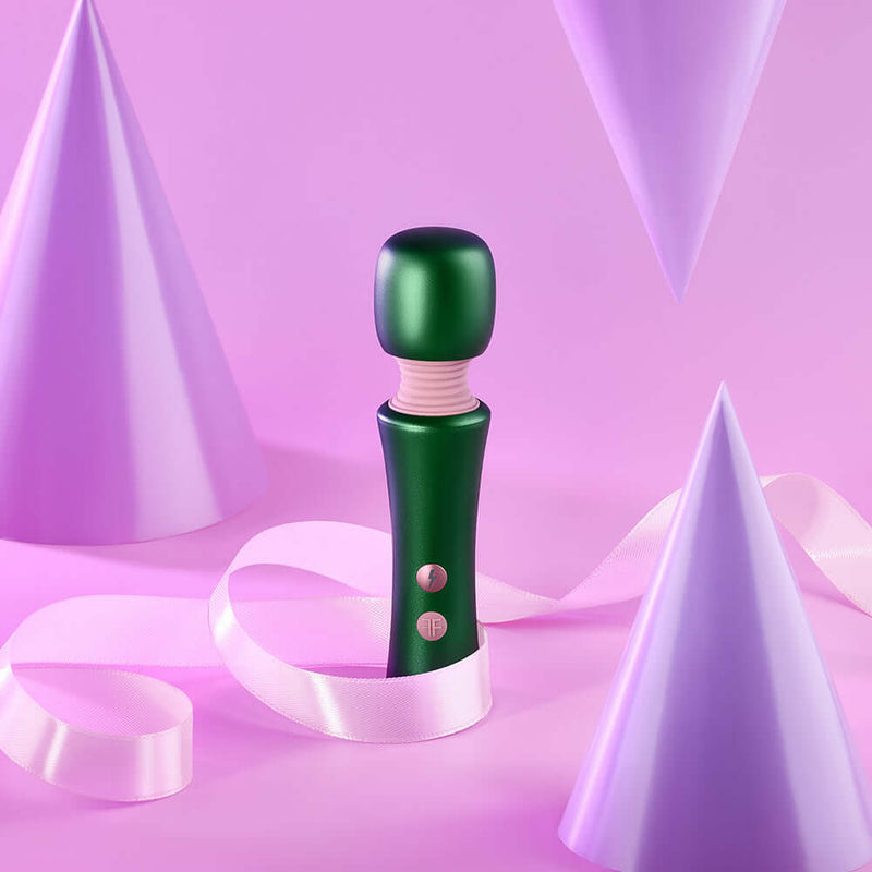 FemmeFunn Bougie Wand Massager Green surrounded by purple party hats and ribbons on a pastel background.