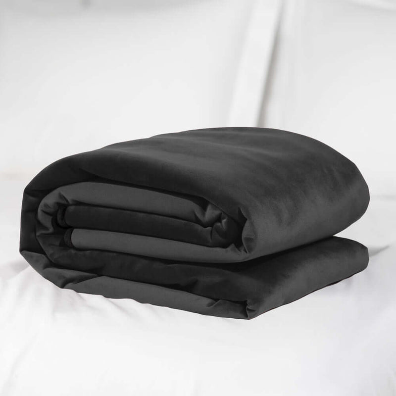 Liberator Fascinator Mini Waterproof Throw Blanket Black folded on a bed.