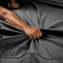 Close-up of a hand gripping the Liberator Fascinator Mini Waterproof Throw Blanket Black, showcasing its plush texture.