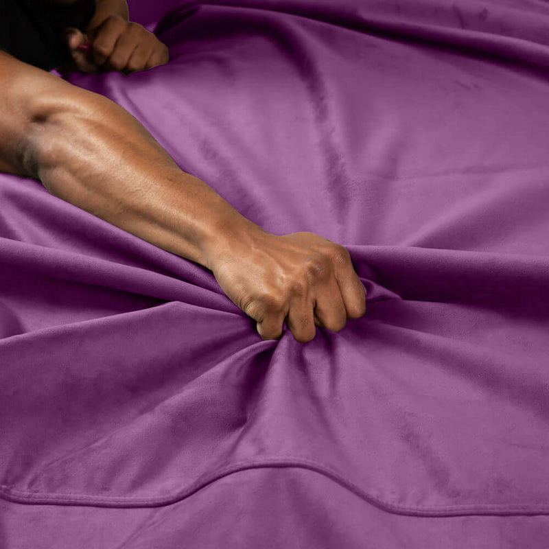 Hand gripping the soft texture of the Liberator Fascinator Waterproof Throw Travel Blanket Purple.